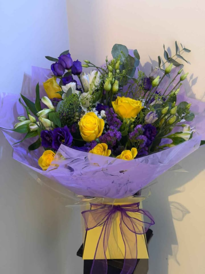 Golden Twilight Hand-Tied - A striking hand-tied bouquet that pairs rich jewel tones with soft golden highlights for a look that feels both vibrant and elegant. Finished in delicate lilac wrapping with a coordinating ribbon, this arrangement has a beautifully fresh, airy style with plenty of natural movement.

Perfect for birthdays, celebrations, or sending a thoughtful gift, this bouquet brings colour, charm, and a touch of sophistication to any occasion.