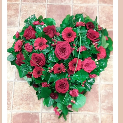 Heart - A striking heart-shaped funeral tribute created in rich crimson tones with glossy greenery and delicate berry accents. Symbolising deep love, remembrance, and devotion, this elegant arrangement offers a meaningful and heartfelt farewell to someone forever cherished.